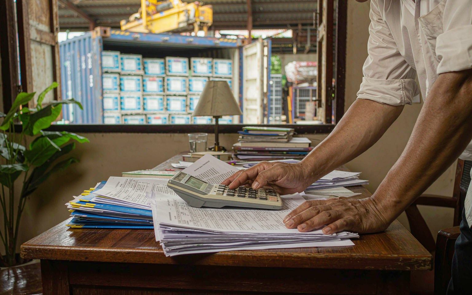Freight forwarder calculating the CIF landed cost of a solar shipment with invoices and duty receipts at Port Moresby
