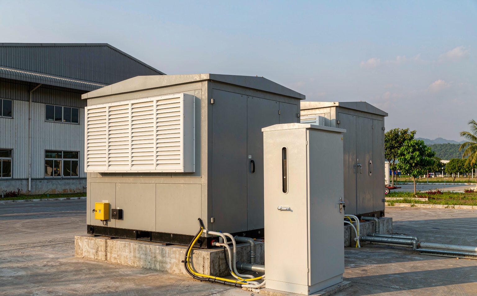 Containerised commercial BESS Philippines installation on a concrete pad beside a factory building