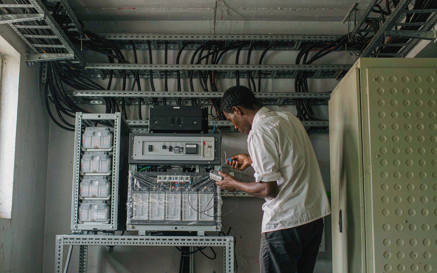 Engineer commissioning a hybrid inverter and LFP battery bank at an African site