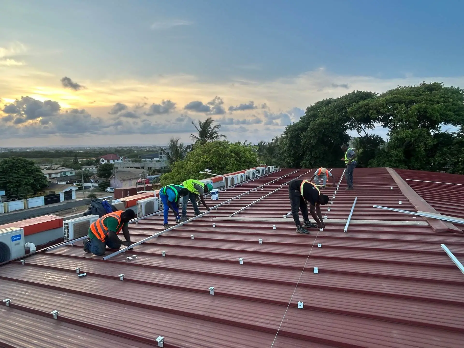 Mars Solar technicians installing solar mounting rails on a metal roof in Ghana
