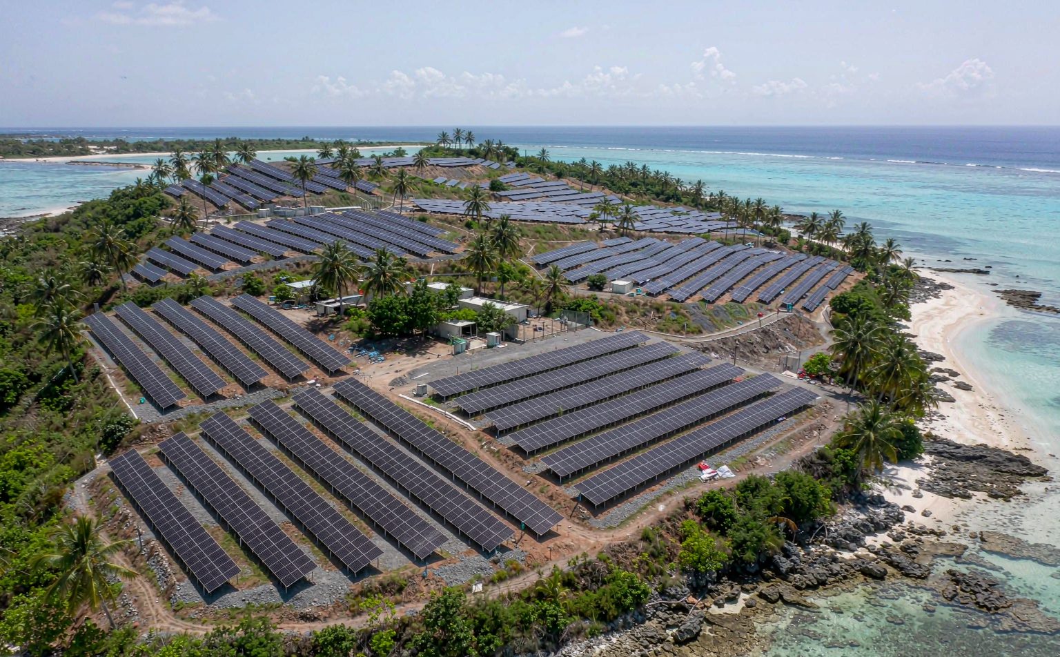 Aerial view of an off-grid solar Philippines island microgrid with PV arrays, a battery container and turquoise sea